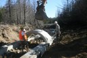Project SHARE and MEFRO employees assist Moosehorn Refuge's excavator operator in installing a new, open-bottom, concrete culvert.